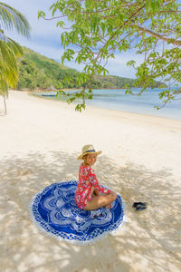 Woman in hat at beach against sky