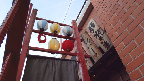 Low angle view of japanese lanterns hanging by brick wall