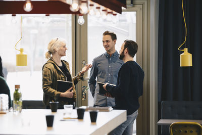 Businesswoman discussing with male colleagues in brightly lit office