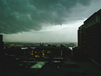 Illuminated cityscape against cloudy sky