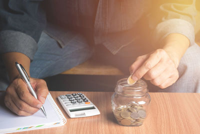 Midsection of man doing calculation at table