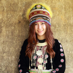 Portrait of smiling woman in traditional clothing against wall