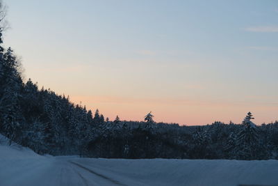 Scenic view of snow covered field against sky during sunset