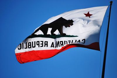 Low angle view of flag against clear blue sky