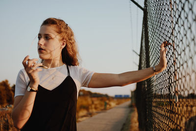 Mid adult man standing by fence against sky