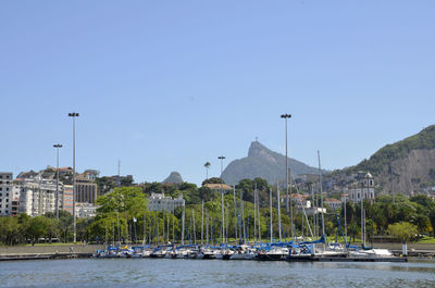 Boats moored on river by mountains against clear sky