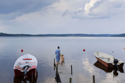 Rear view of people on boat in sea against sky