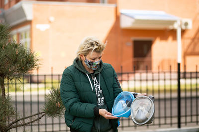 Mid adult woman standing against building