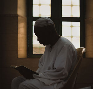 Side view of an old man reading the quran in a mosque 