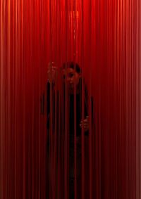 Portrait of woman standing amidst red curtain