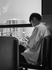 Rear view of boy sitting on chair in bus