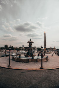 Statue in city against cloudy sky