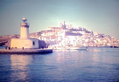 Lighthouse amidst buildings in city against clear sky