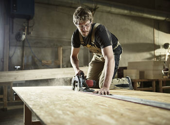 Carpenter sawing wood with handsaw