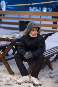 Portrait of teenage boy in skates sitting on snow 