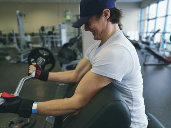 Side view of man lifting barbell in gym