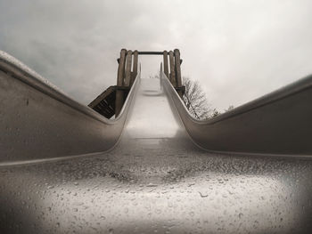 Low angle view of wet slide against sky
