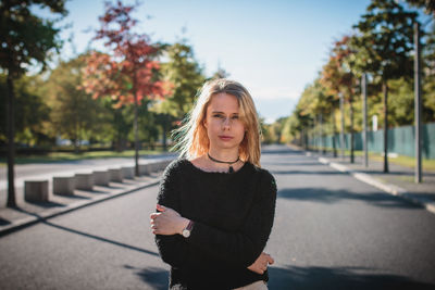 Portrait of young woman standing on road