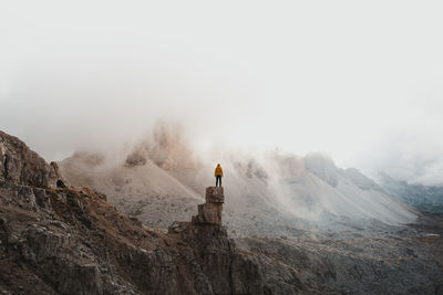 Rear view of man standing on rock against landscape