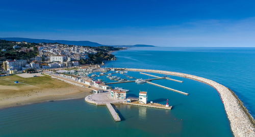 High angle view of buildings by sea against blue sky