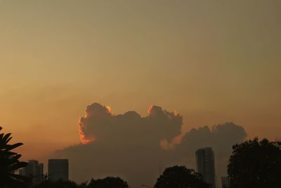 Silhouette trees and buildings against sky during sunset