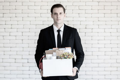 Portrait of a young man standing against wall