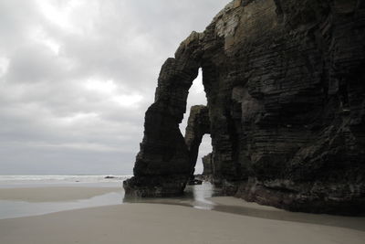 Rock formation on beach against sky