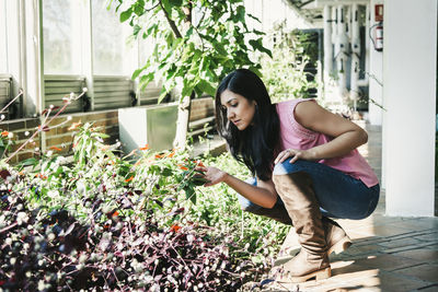 Young woman standing against potted plants