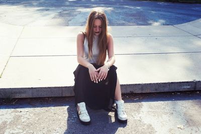 Portrait of young woman sitting on skateboard ramp