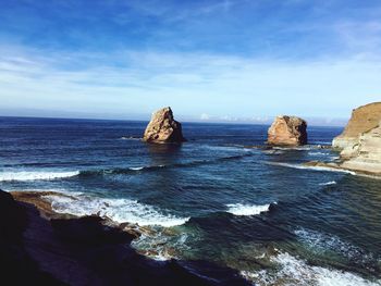 Scenic view of rocks in sea against sky