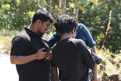 Friends standing on a man in forest