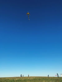 People paragliding against clear blue sky
