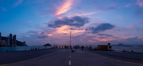 Street by sea against sky during sunset