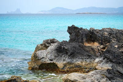 Rock formation on sea shore against sky