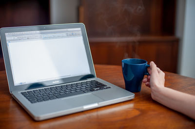 Close-up of laptop and coffee cup on table