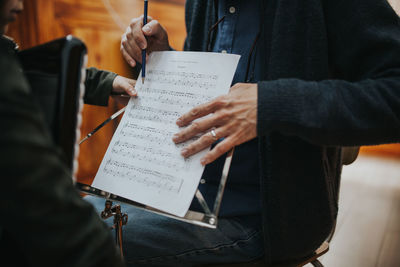 Midsection of man teaching music to student