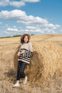 Young woman standing on field against sky