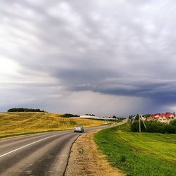 Country road against cloudy sky