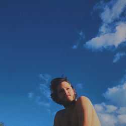 Low angle portrait of young woman against blue sky