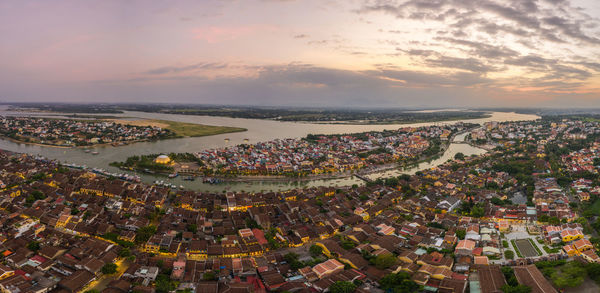 High angle view of townscape by sea against sky during sunset