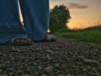 Low section of man sitting on land against sky