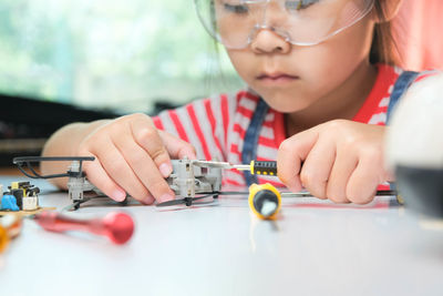 Girl repairing object with tool on table in training class