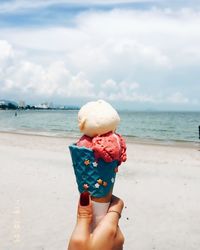 Hand holding ice cream cone on beach