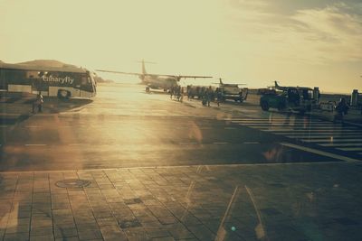 Group of people on airport runway against sky