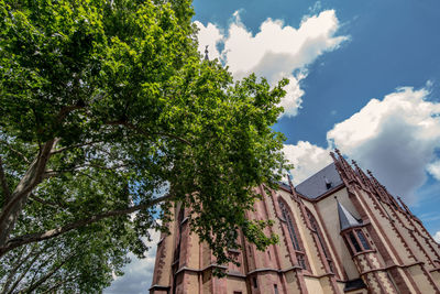 Low angle view of trees and building against sky