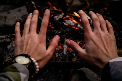 Cropped hands of man gesturing against campfire