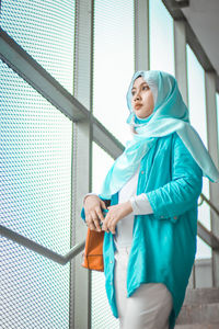 Low angle view of thoughtful young woman looking through window