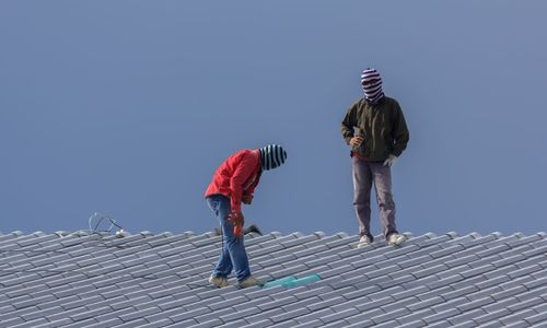 Low angle view of people on rooftop against clear sky