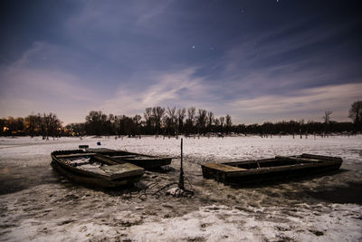 Abandoned boat on snowy field against sky during winter