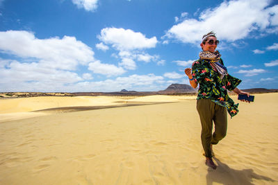 Woman standing on sand dune in desert against sky